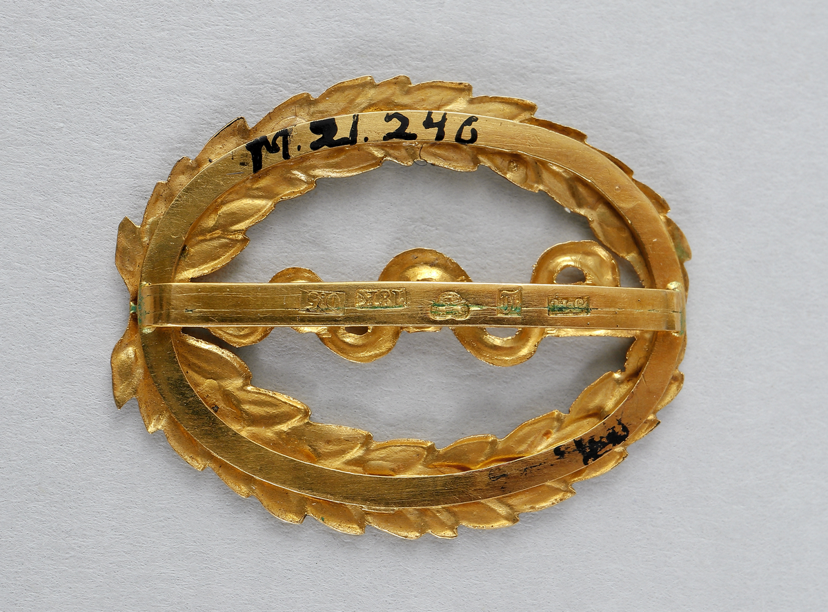 Examenstecken. Guldemblem för medicine doktorsexamen. Emblemet (ovalt) föreställer en orm som slingrar upp på en trädstam, omgiven av en oval lagerkrans. På baksidan finns stämplar.

Inskrivet i huvudbok 1969.