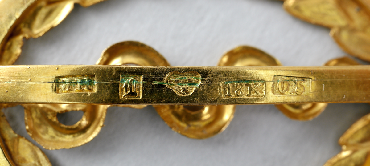 Examenstecken. Guldemblem för medicine doktorsexamen. Emblemet (ovalt) föreställer en orm som slingrar upp på en trädstam, omgiven av en oval lagerkrans. På baksidan finns stämplar.

Inskrivet i huvudbok 1969.