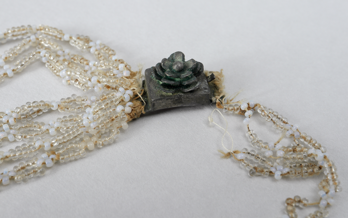 Halsband (M 3525 a) består av stålpärlor med silverlås. 

Halsband (M 3525 b) består av glaspärlor i olika färger (vita, svagt gröna, metallglänsande och ofärgade). Det har fem rektangulära pärlbroderier sammanbundna med sju länkar vardera. Lås saknas. Broderiplattornas storlek 28 x 24 mm.