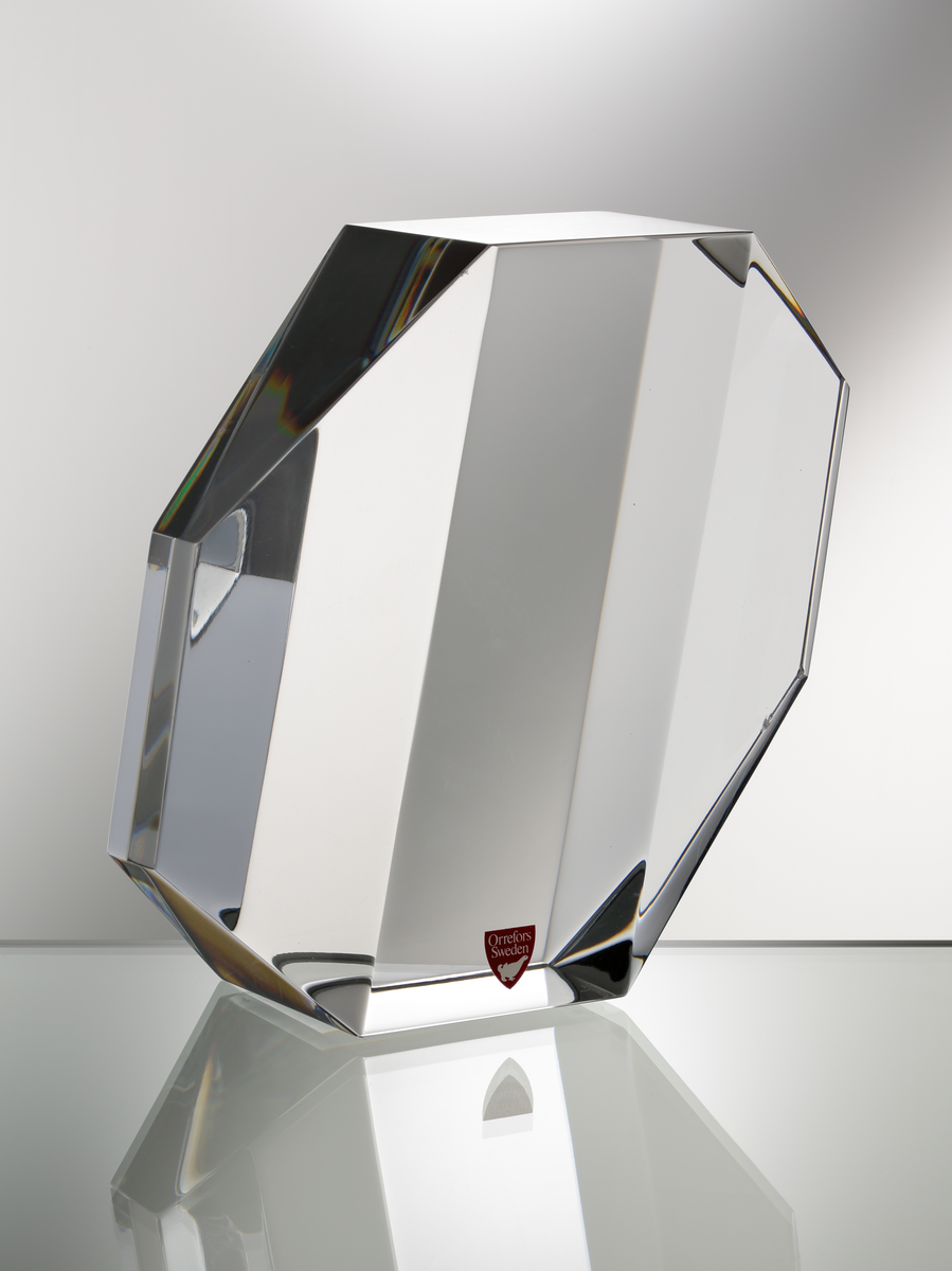 Formgivare: Jan Johansson. Skulptur, "Reflexioner". Massivt klarglas med sexkantig fasetterande form, brutna hörn och diagonalt slipade gavlar.
