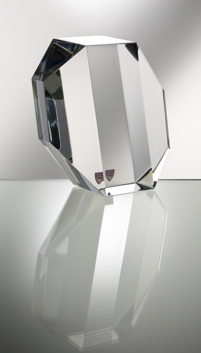Formgivare: Jan Johansson. Skulptur, "Reflexioner". Massivt klarglas med sexkantig fasetterande form, brutna hörn och diagonalt slipade gavlar.