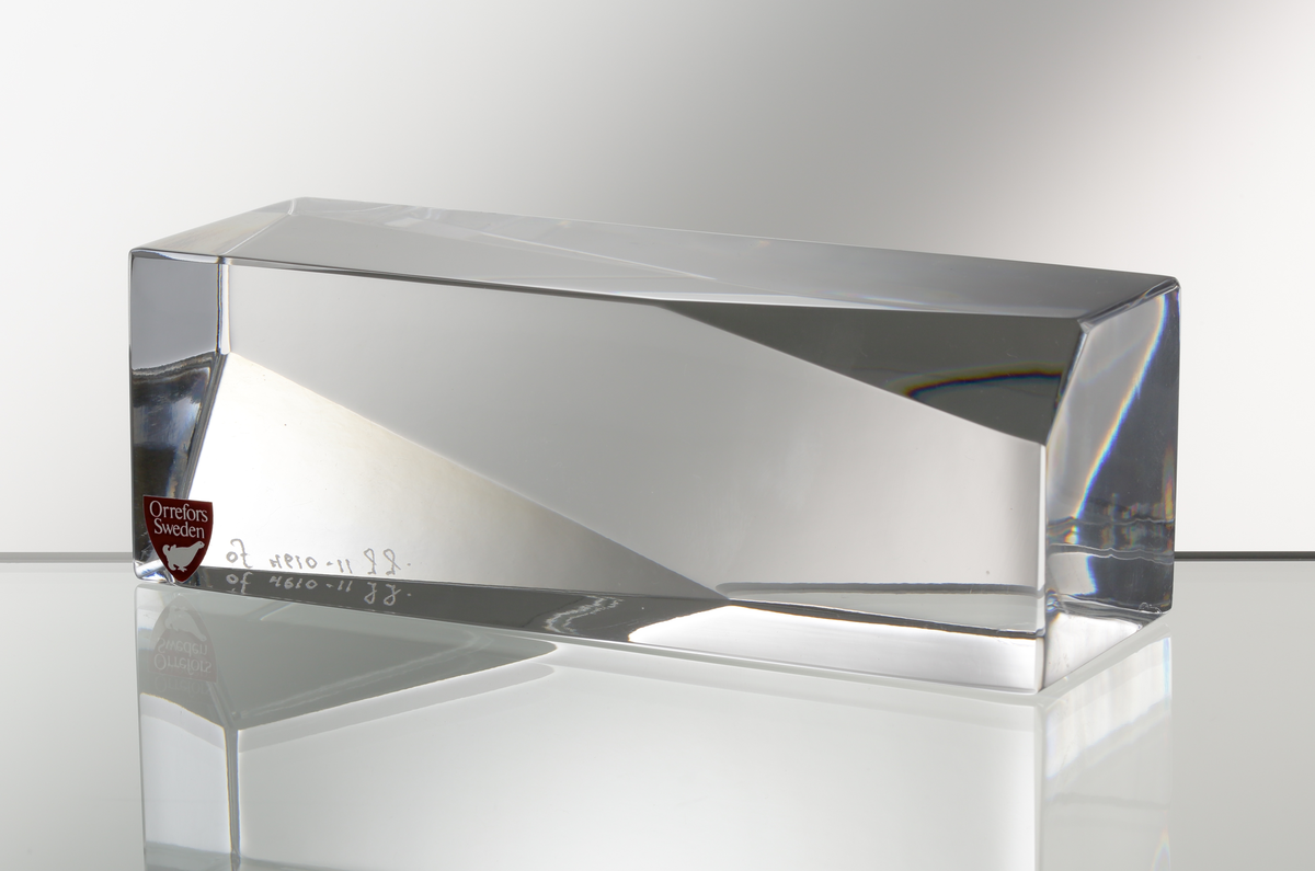 Formgivare: Jan Johansson. Skulptur "Jord". Massivt glas med rektangulär liggande form. Två diagonala hörn med triangulärt
slipad yta.