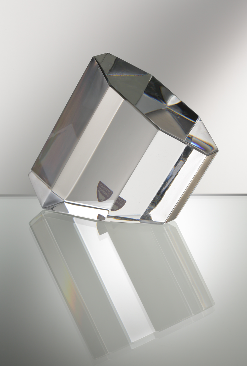 Formgivare: Jan Johansson. Skulptur "Oktav". Massivt glas med åttkantig fasetterande form och diagonalt slipad bas.