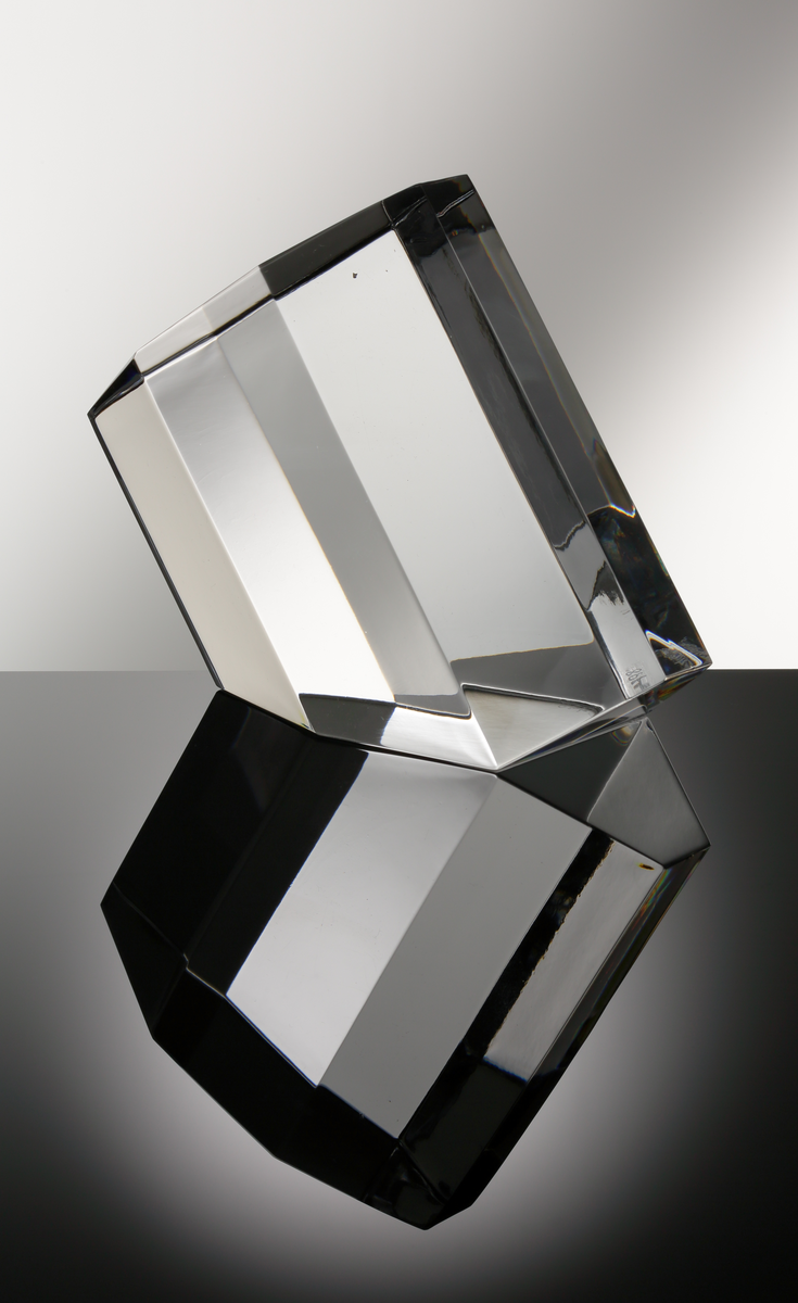Formgivare: Jan Johansson. Skulptur "Oktav". Massivt glas med åttkantig fasetterande form och diagonalt slipad bas.

