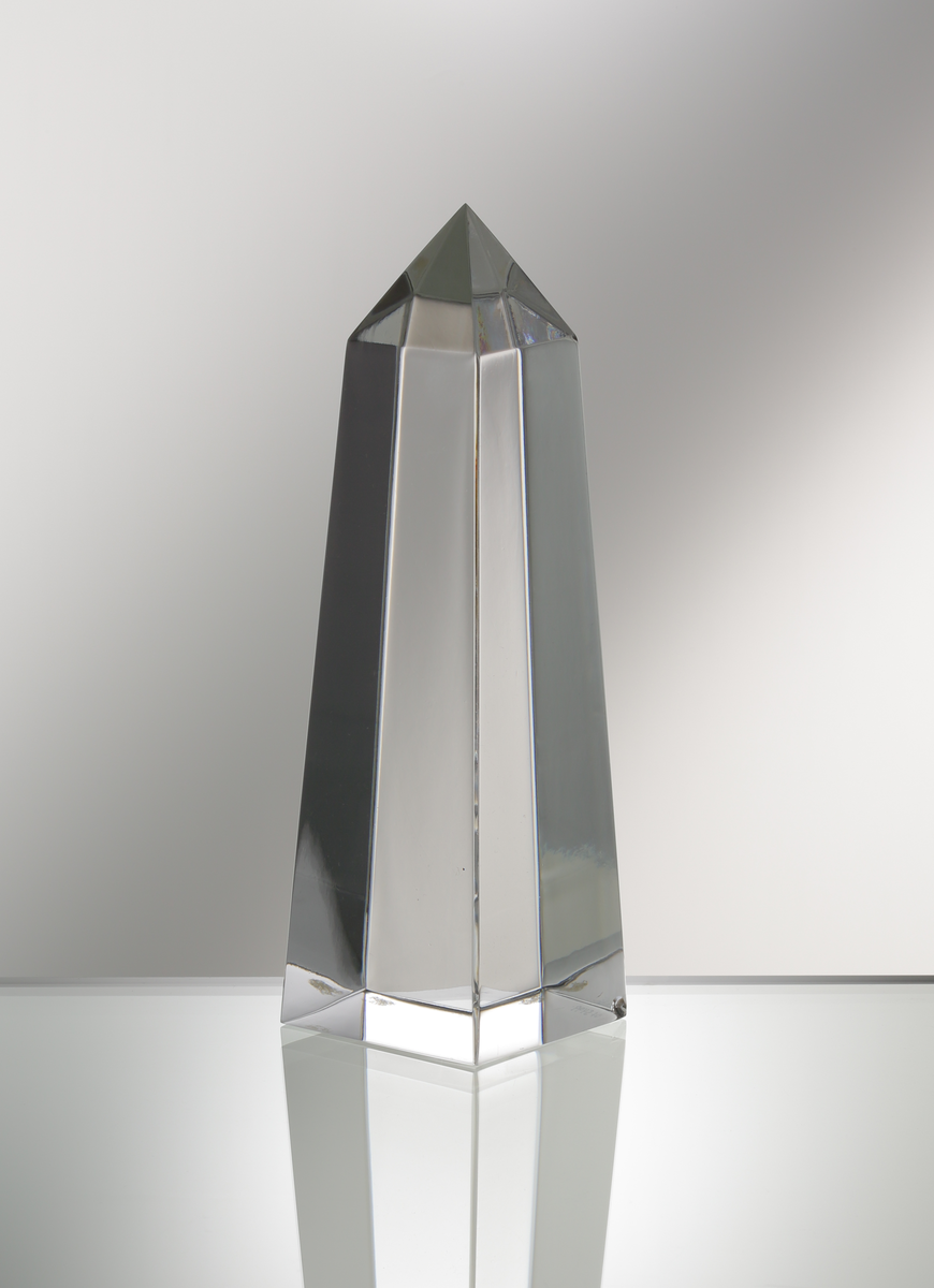 Formgivare: Jan Johansson. Skulptur "Obelisk". Massivt glas med kvadratisk profil som smalnar av mot pyramidformad topp.
