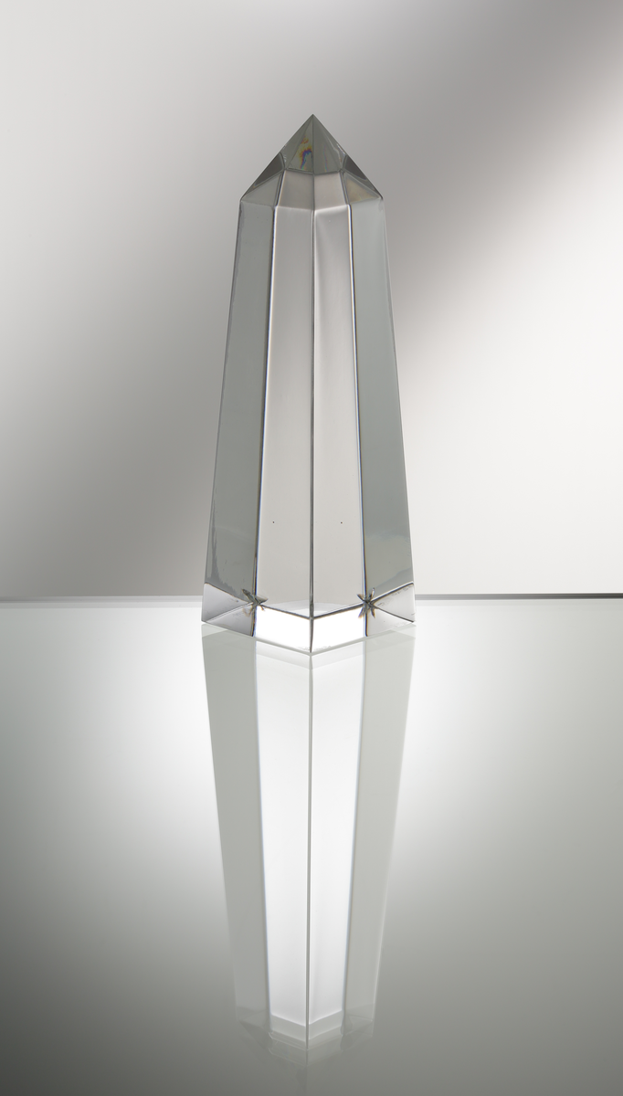 Formgivare: Jan Johansson. Skulptur "Obelisk". Massivt glas med kvadratisk profil som smalnar av mot pyramidformad topp.