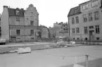 Nedslag i Linköping våren 1975 med inslag av både bevarade såsom efter bildens tillkomst rivna hus. Redan rivna var husen i det upplösta kvarteret Enviget i bildens förgrund. Vid tiden uppläts ytan som bilparkering i väntan på ny byggnation. Till vänster ståtar det vackra och kvarstående stenhuset på adressen Läroverksgatan 4. Läroverksgatan 1 till höger kom dock att rivas. I bildens centrum vänder Stenhusgården sin södra gavel mot betraktaren, i sin helhet en manifestation av oföränderlighet.
