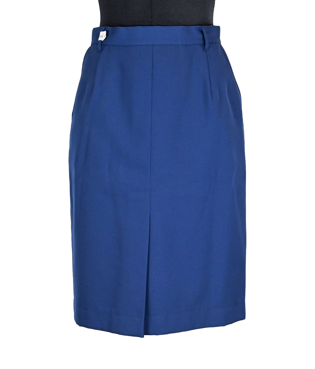 Kjol i mörkblå textil till ämbetsdräkt för kvinnlig personal vid Luftfartverket. Kjolen har två enkla framfickor. Längs midjan sitter fyra hällor för bälte. I bak i plaggets nederkant finns ett gångveck. Kjolen stängs i bak med dragkedja och knapp. Fodringen är mörkblå. 

På insidan i bak sitter två lappar med information om tillverkare och storlek. På ena lappen finns även Luftfartsverkets logga. Kjolen är producerad av Confetti i storlek C40. I en av hällorna sitter en papperslapp med nummer 8632. På denna har texten 3/10 påförts i bläck.