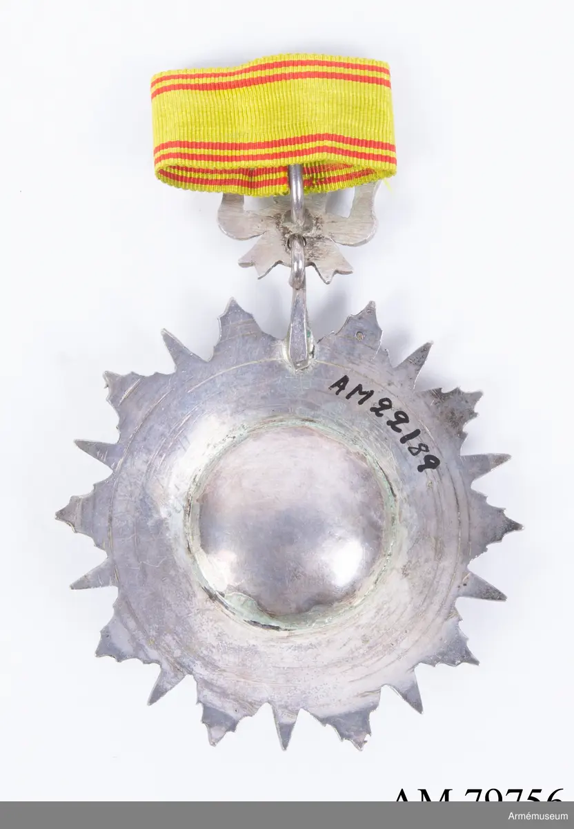 Ordenstecken för kommendör.

En tiouddig stjärna (varannan spets av röd, varannan av grön emalj, varje spets längs mitten avdelad av en silverrand); stjärnan är lagd på en tiouddig facetterad silverkraschan.

Ovanpå stjärnan en rund sköld, omgiven av en ring med briljantslipade silverfacetter. Skölden är av grön emalj, och å densamma läses i silverslingor den regerande beyens  namnchiffer.

Ordenstecknet är fäst vid en silverrosett.

Bandet, ljust mossgrönt, har två smala, röda ränder på vardera sidan. Flera lösa samhörande band.
//Kompl. beskr. PRN