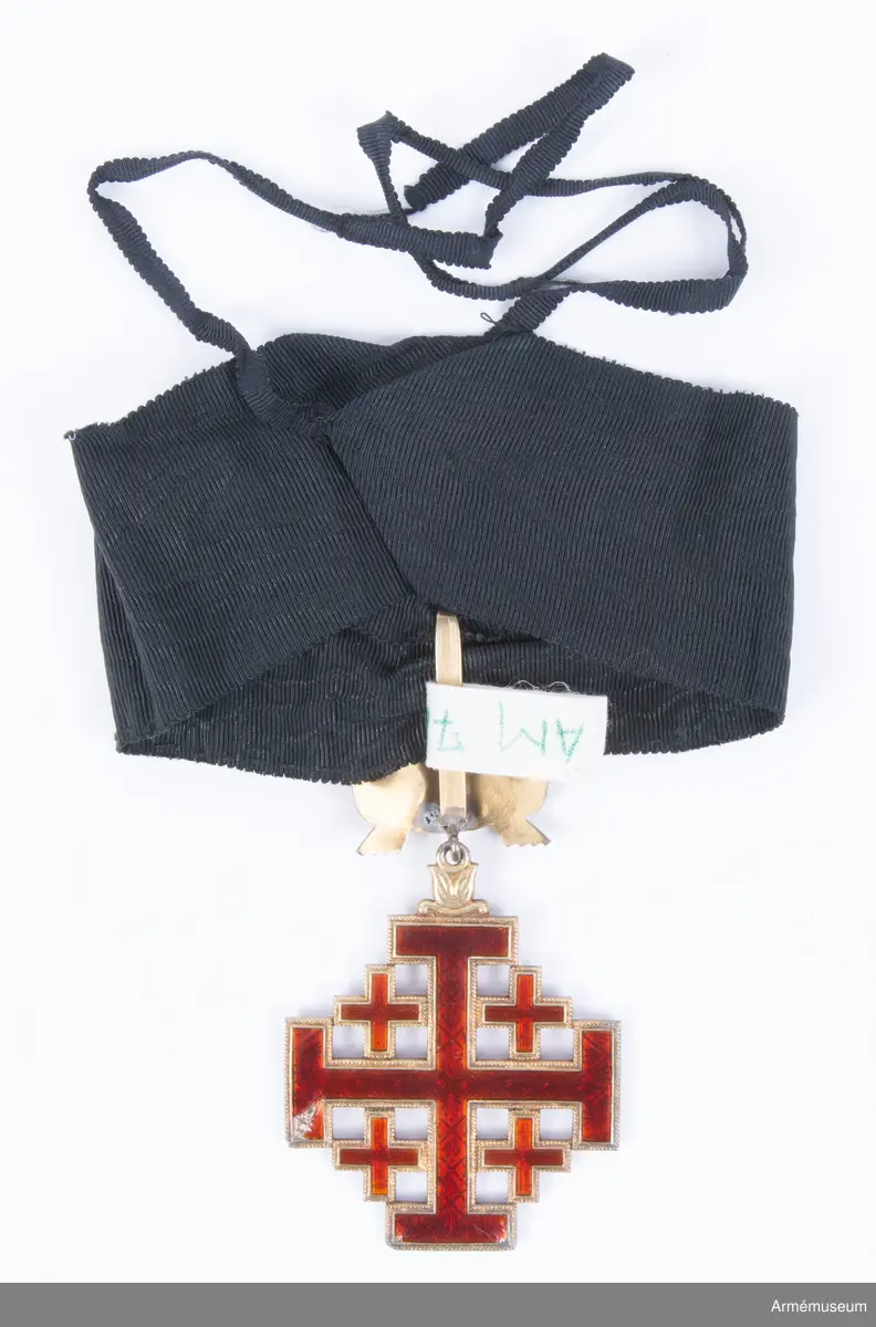 Påvliga Heliga Gravens orden, kommendörstecken i svart band. 
Miniatyr och knapp. Ordenstecknet i form av pilgrimssnäcka tilldelades ordensriddare som genomfört en pilgrimsresa till det heliga landet.

Förvaras i samhörande etui.