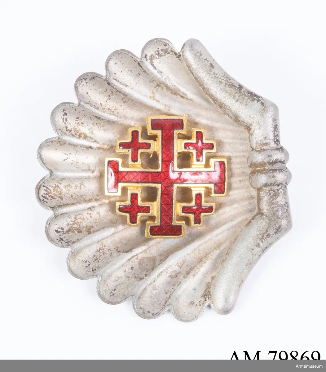 Påvliga Heliga Gravens orden, kommendörstecken i svart band. 
Miniatyr och knapp. Ordenstecknet i form av pilgrimssnäcka tilldelades ordensriddare som genomfört en pilgrimsresa till det heliga landet.

Förvaras i samhörande etui.