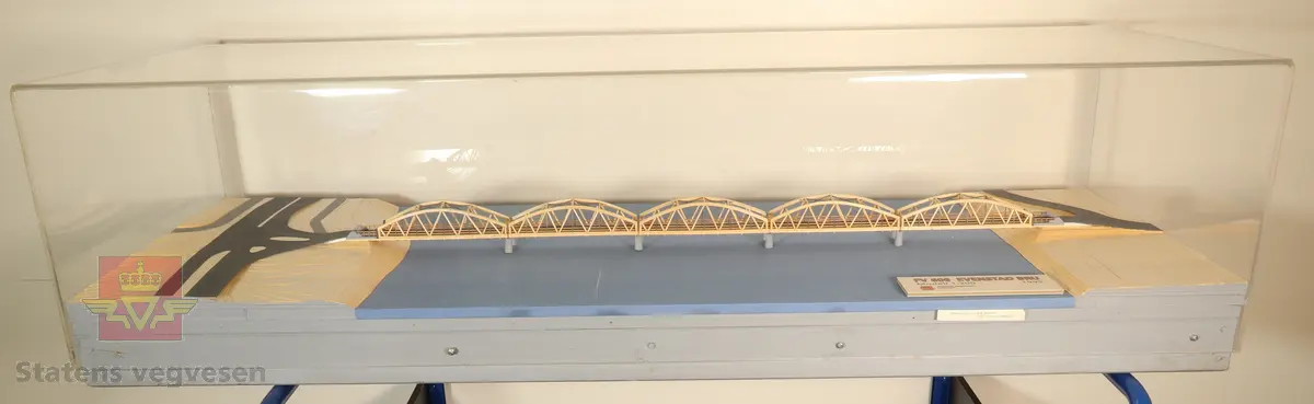 Miniatyr bru i målestokk 1:200. Laget av papir, tre og metall. Står i monter laget av tre og plast.