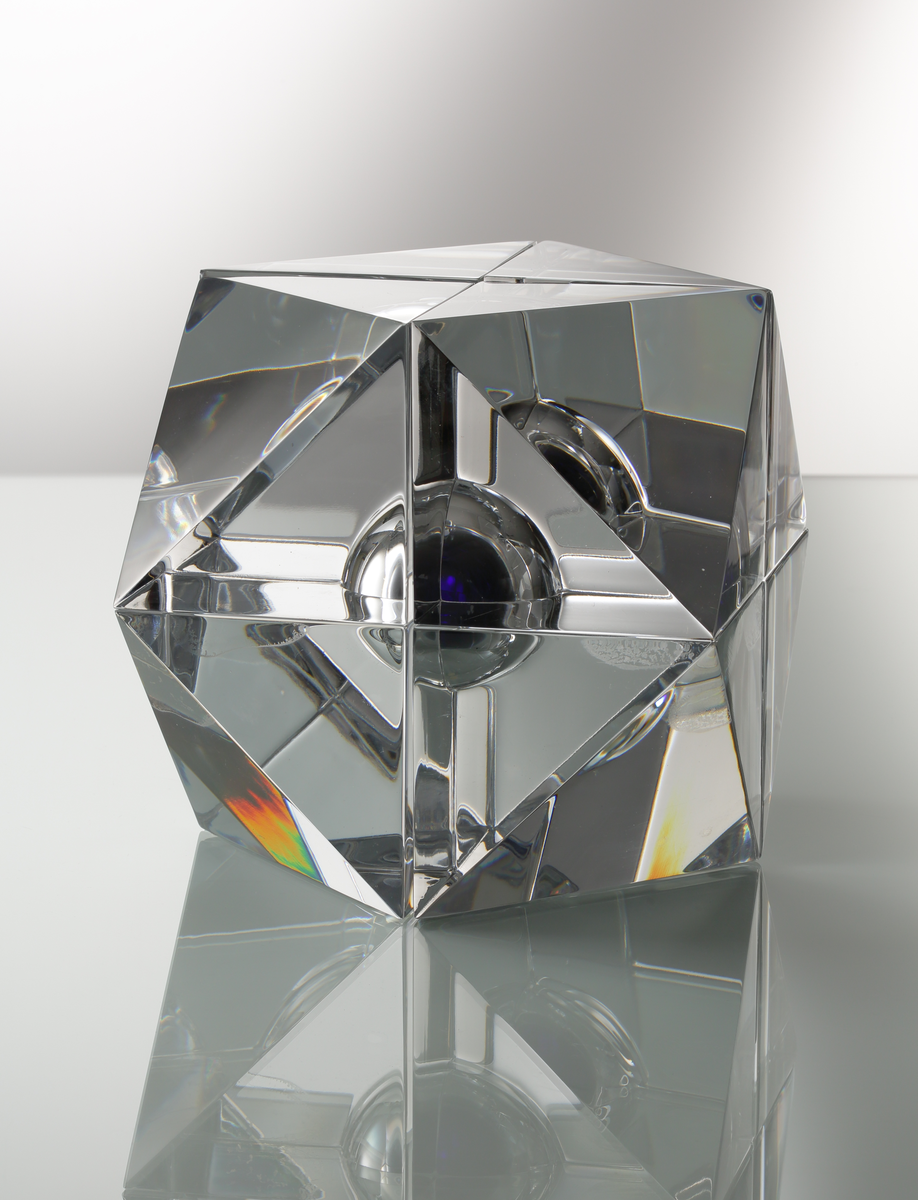 Formgivare: Jan Johansson. Skulptur i massivt klarglas, sjudelad geometrisk form med kula i blåtonat glas.