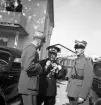 Kung Gustaf V:s besök i Liatorp 1939. 
I väntan på kungen. Några herrar i uniform står vid några bilar och pratar m.m.