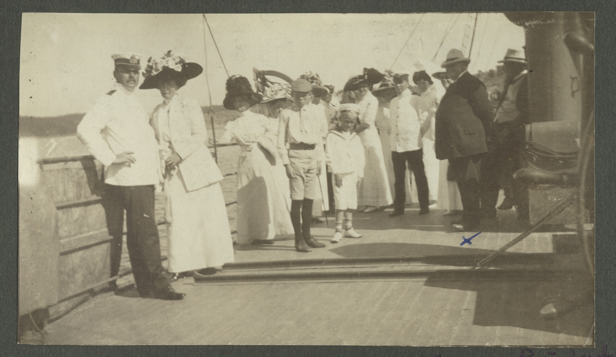 Party ombord på Blenda i Stenungsund 1911. Tre finklädda damer lutar sig mot religen på däck. Till vänster i bild syns kapten Gisiko.