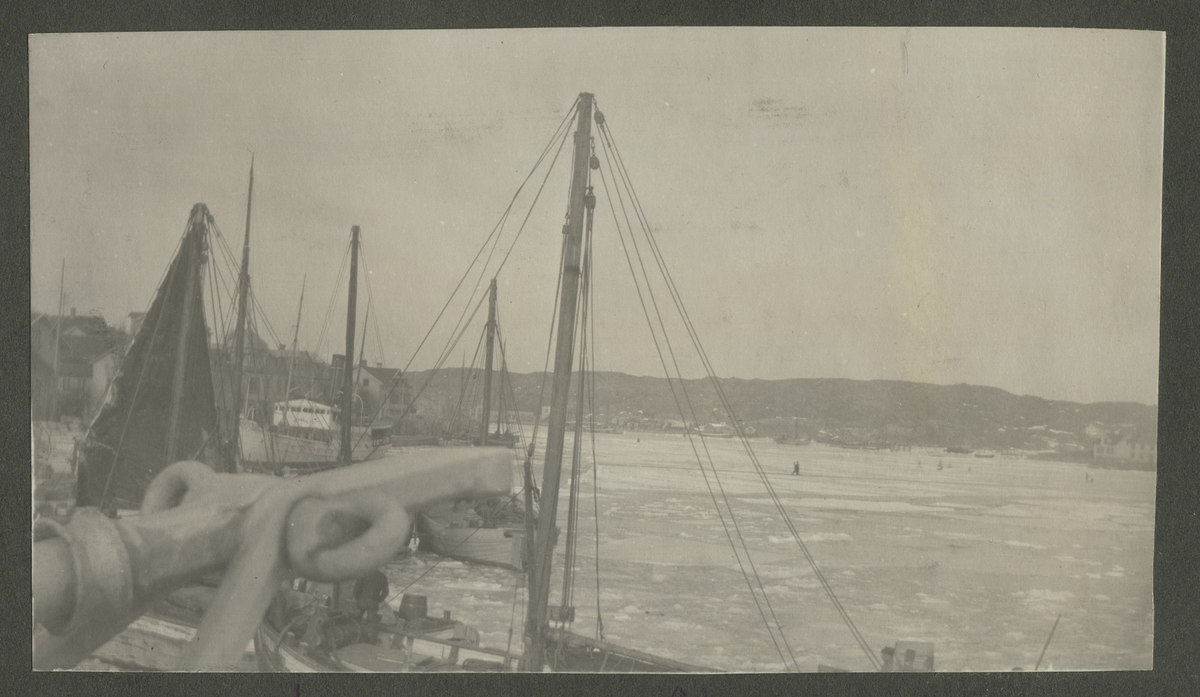 Båt omgiven av en samling personer som står på närliggande brygga under vintertid. Marstrand 1916-1917. Isen låg fast till Skagen i 14 dagar.