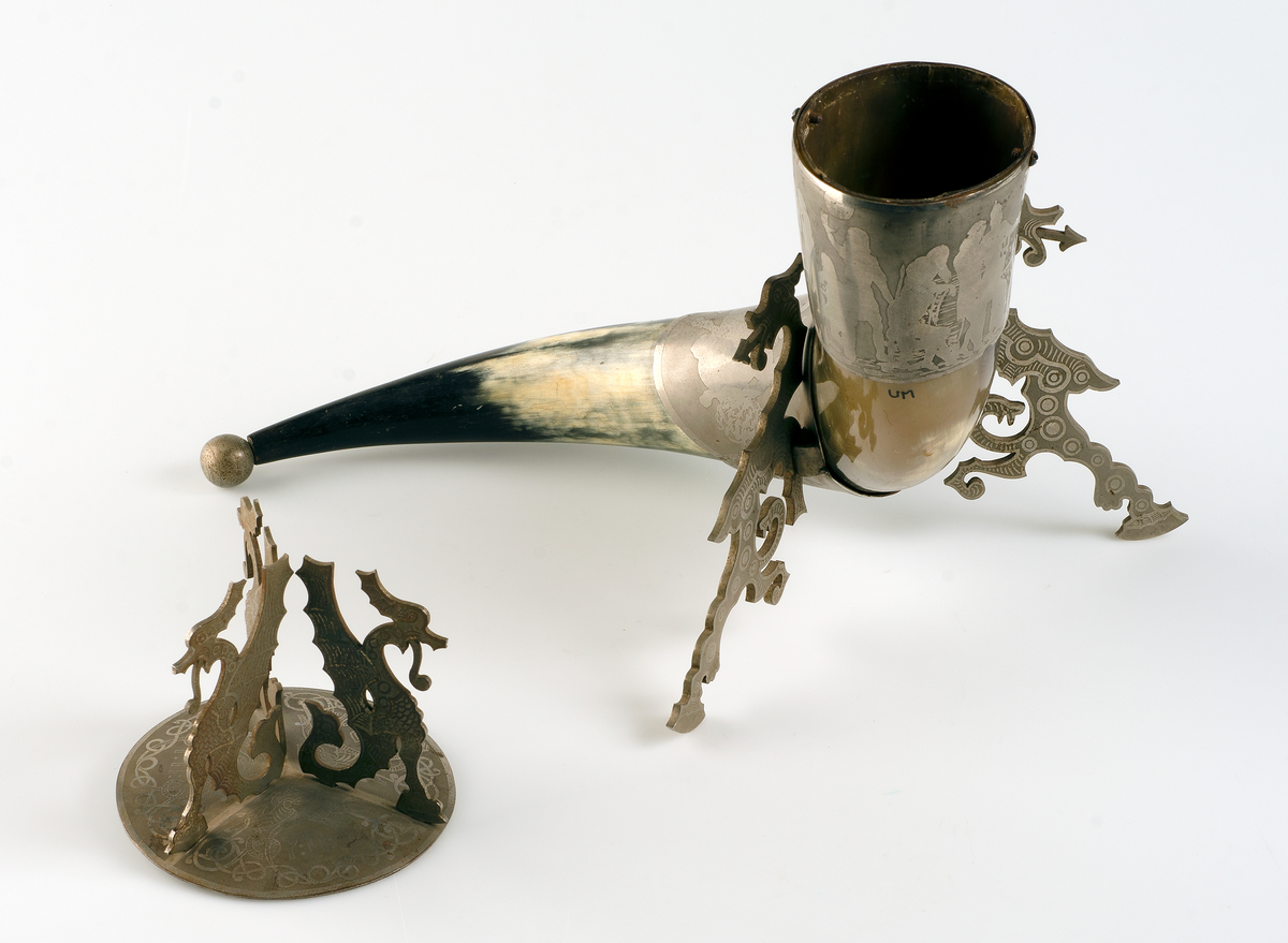 Gulvitt horn med beslag och lock av silverimiterande metall. På lockets översida runor och slingor i fornnordisk drakstil. På lockets undersida ingraverat: Jag kom i arf till en skolgosse i Sept 1861. Kom med en student till Akad 18 13/9 74: bofästes och invigdes 18 13/9 81 och har under dessa 20 år likväl ej ombytt ägare. 
På beslagen "vikingascener".
 
