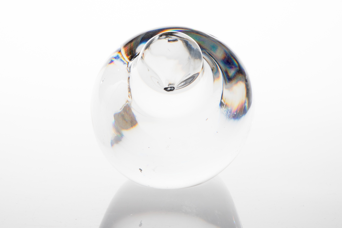 Glassfigur i massivt klart glass uten dekor. Figuren har en stilisert fugleform, og skal forestille en rype.