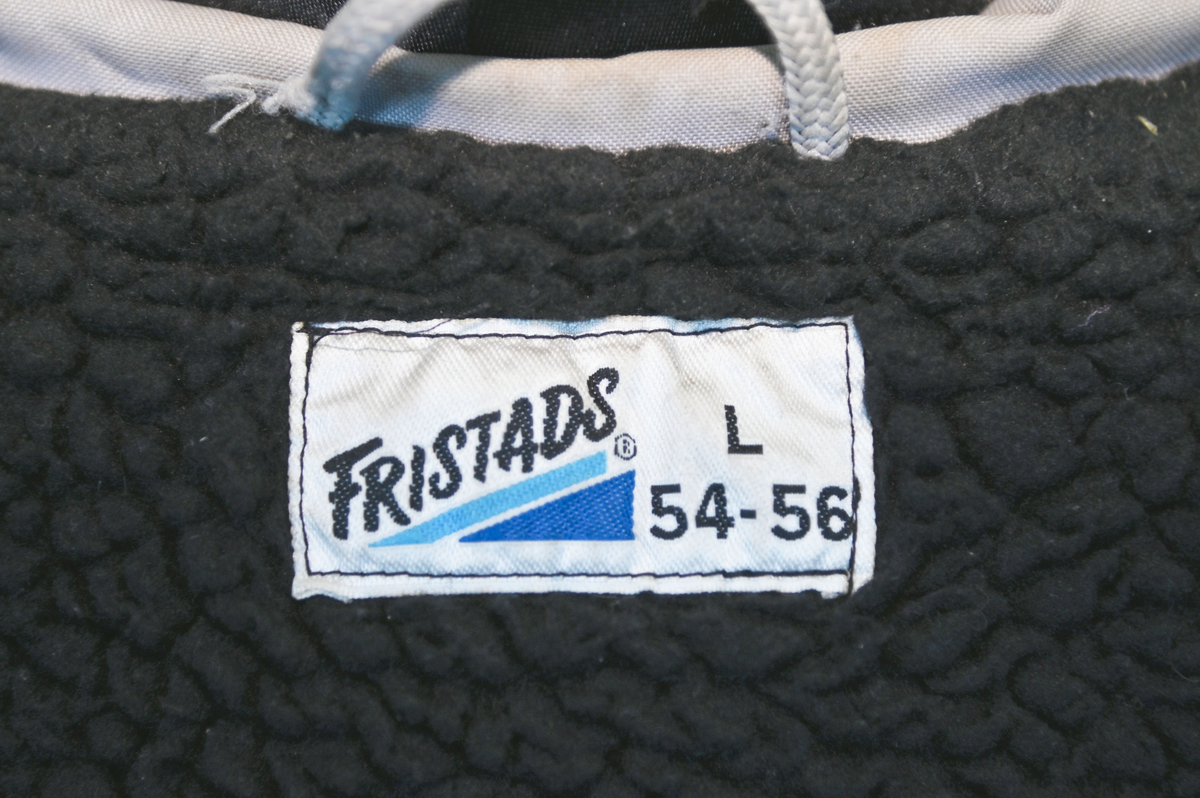 Grå varseljacka med svart foder tillhörande anställd på Luftfartsverket. Jackan har flera fickor som stängs med dragkedja eller kardborreband, samt en innerficka på vänster sida. Jackan är försedd med reflexer på båda ärmslut och båda framfickor. Luftfartsverkets logga sitte på höger bröst och ryggen. I jackan sitter en lapp med tvättanviselser. Jackan stängs med dragkedja i plast och sex stycken tryckknappar. Det finns även tryckknappar runt kragen för en eventuell luva som saknas. Jackan är väl använd och har flertalet smuts- och oljefläckar.

Jackan är i storlek L (54-56).