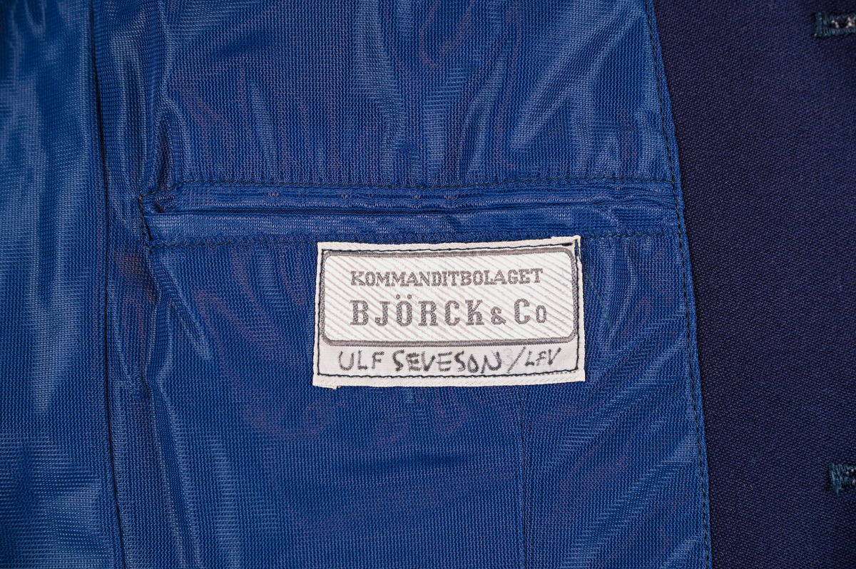 Väst till ämbetsdräkt för Luftfartsverket. Västen är av mörkblå ylle med enkel knäppning med tre stycken plastknappar. Framtill finns totalt tre stycken fickor, två midjeficor samt en bröst ficka på vänster sida. I fodret finns en innerficka på vänster sida.

Västen är tillverkad av Kommanditbolaget Björck & Co.