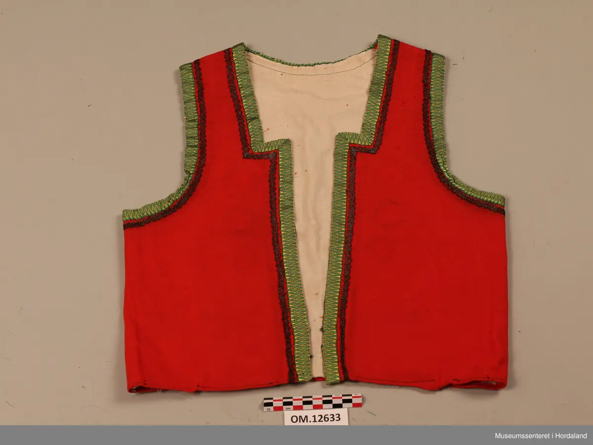 Raudt bunadsliv med grøne og gule silkekvardar (-band) rundt opningane. Innafor silkekvardane er det sydd på ei sølvsnor. Sidesaumane er trekte bakover (skrådde) på ryggen. Tre hekter i livet framme (kroker og maljer). På framstykket viser det at livet har hatt to innsnitt på kvar side tidligare. Sameleis kan ein sjå at her har vore påsydd tre borer på kvar side langs opninga framme. Det viser som svarte ringar på stoffet. Livet er nokså slitt og velbrukt. Både ullstoffet og bomullslerretet i livet er nokså tynt.