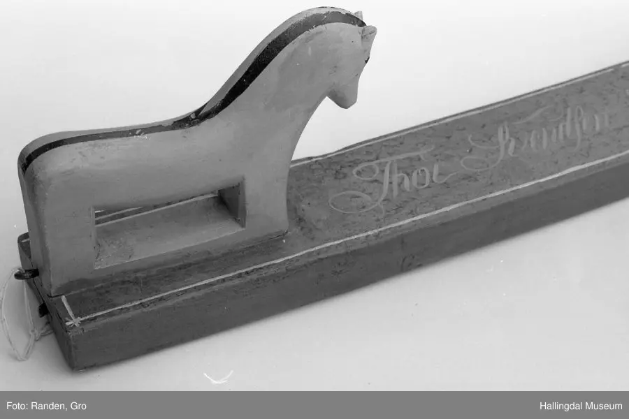 Mangletre m/ rull. Raudbrunt på ovasida med innskrifta "Thor Svendsen Sand 1871" i gult, blå kantar, gul hest med svart man.