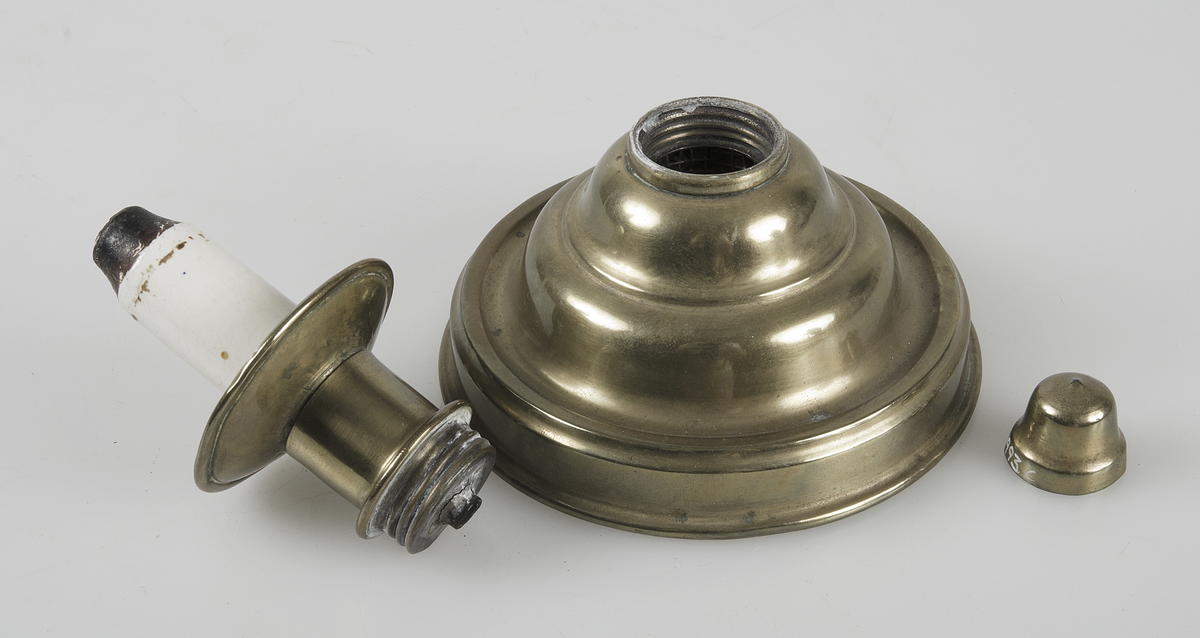 Oljebehållaren-foten av mässingsplåt, botten av plåt. Brännare som kan skruvas bort från foten, samt hatten av mässingsplåt. Ljus av vitt porslin.
Veken saknas.


