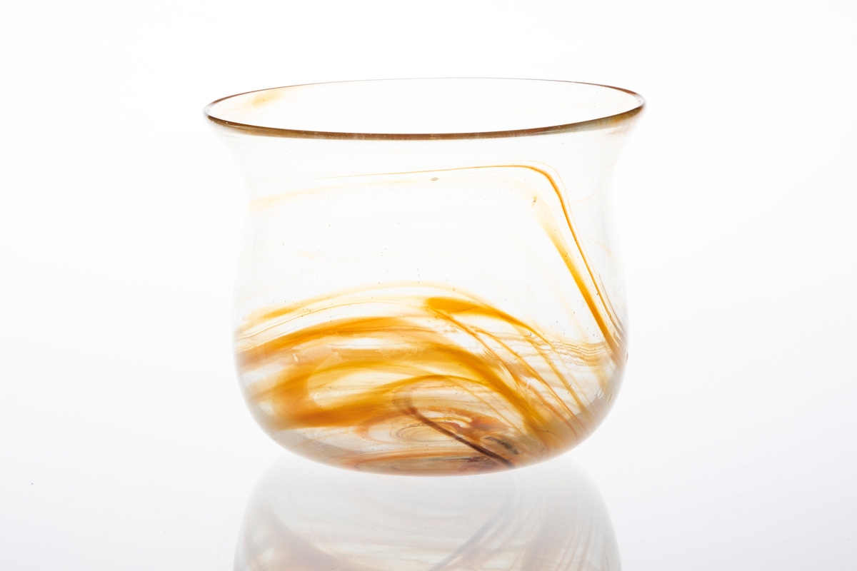 Glassbolle i klart glass. Bollen har kuleformet korpus med utoverbrettet munningsrand. I det klare glasset er det rød- og oransjefargde partier som slynger seg rundt korpus.