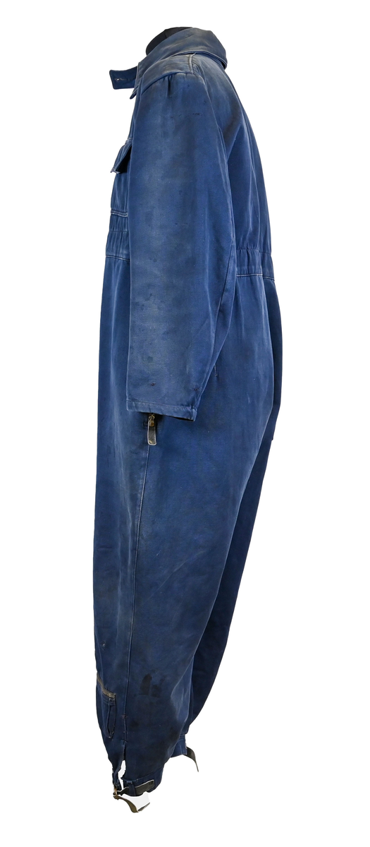 Mekanikeroverall i blå denim från Östgöta flygfottilj, F3. Overallen har två bröstfickor med lock som försluts med metallknapp. Längs ner vid fotändarna sitter en mindre ficka på vardera ben som sluts med dragkedja. På vardera sida vid midjan sitter fickor med dragkedja och löpare i skinn. På baksidan finns en bakficka på höger ben. Overallen har en krage som går att vika upp och stänga med två tygband och metallknappar. Den yttersta knappen på rad två av knappar sitter löst, Kragen går att vika ner och fästa i overallen med tryckknappar i metall. På insidan av midjan sitter en dragsko. Fotändarna kan spännas med en skinnrem. Overallen stängs med dragkedja i metall. 

På plaggets insida finns ett vitt tryck med texten "F3 2". F3 talar om att overallen användes vid Östgöta flygfottilj. 2:an anger troligtvis storleken på plagget.

Overallen har fyra stycken lagningar nere på höger baksida.