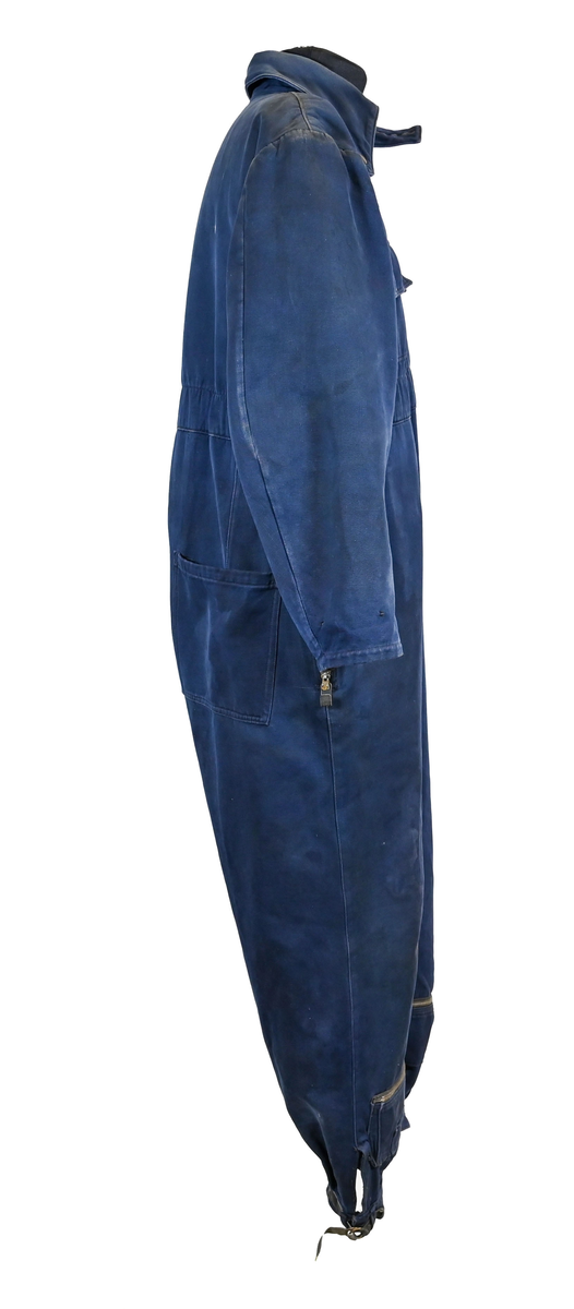 Mekanikeroverall i blå denim från Östgöta flygfottilj, F3. Overallen har två bröstfickor med lock som försluts med metallknapp. Längs ner vid fotändarna sitter en mindre ficka på vardera ben som sluts med dragkedja. På vardera sida vid midjan sitter fickor med dragkedja och löpare i skinn. På baksidan finns en bakficka på höger ben. Overallen har en krage som går att vika upp och stänga med två tygband och metallknappar. Den yttersta knappen på rad två av knappar sitter löst, Kragen går att vika ner och fästa i overallen med tryckknappar i metall. På insidan av midjan sitter en dragsko. Fotändarna kan spännas med en skinnrem. Overallen stängs med dragkedja i metall. 

På plaggets insida finns ett vitt tryck med texten "F3 2". F3 talar om att overallen användes vid Östgöta flygfottilj. 2:an anger troligtvis storleken på plagget.

Overallen har fyra stycken lagningar nere på höger baksida.