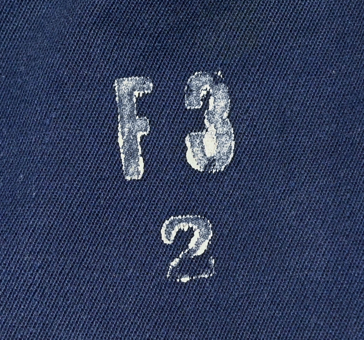 Mekanikeroverall i blå denim från Östgöta flygfottilj, F3. Overallen har två bröstfickor med lock som försluts med metallknapp. Längs ner vid fotändarna sitter en mindre ficka på vardera ben som sluts med dragkedja. På vardera sida vid midjan sitter fickor med dragkedja och löpare i skinn. På baksidan finns en bakficka på höger ben. Overallen har en krage som går att vika upp och stänga med två tygband och metallknappar. Den yttersta knappen på rad två av knappar sitter löst, Kragen går att vika ner och fästa i overallen med tryckknappar i metall. På insidan av midjan sitter en dragsko. Fotändarna kan spännas med en skinnrem. Overallen stängs med dragkedja i metall. 

På plaggets insida finns ett vitt tryck med texten "F3 2". F3 talar om att overallen användes vid Östgöta flygfottilj. 2:an anger troligtvis storleken på plagget.

Overallen har fyra stycken lagningar nere på höger baksida.