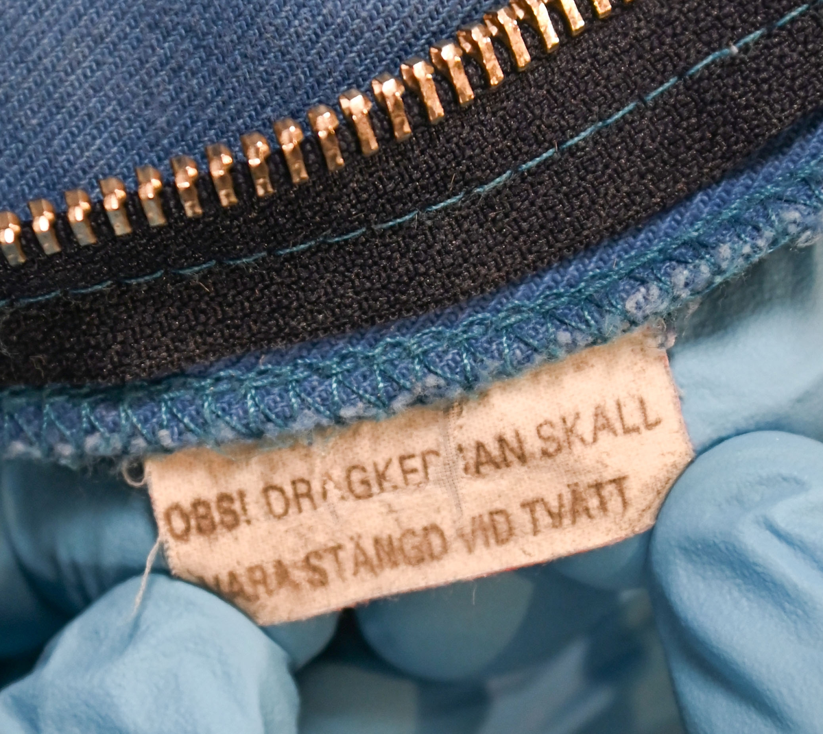 Blå arbetsoverall från SAS. På plagget finns en logga för SAS över vänster bröst och mitt på ryggen. Overallen har två bröstfickor med reflexband som försluts med kardborre. Vänster ficka saknar den del som kopplar an till kardborren på fickan. Frampå sitter två större framfickor med lock och på vardera ben sitter ytterligare två fickor på sidorna. På baksidan finns två stora bakfickor. Högt upp på sidan av vardera ärm sitter ytterligare fickor varav den högra är av genomskinlig plast. Samtliga fickor försluts med kardborre. Utöver på bröstfickorna sitter reflexband runt benens nedre del samt högt upp över ryggen. Overallen sluts med dragkedja och två tryckknappar i metall. Ärmsluten kan justeras med kardborre. Vid höfterna finns två öppningar in i overallen. På knäna finns öppningar för att lägga i knäskydd.

På plagget finns spår av vit färg och andra smutsfläckar. Vänster bakficka är nött.

Overallen är producerad av Fristads i storlek 48. På insidan längs med dragskedjan sitter en lapp med texten "OBS! DRAGKEDJAN SKALL VARA STÄNGD VID TVÄTT".