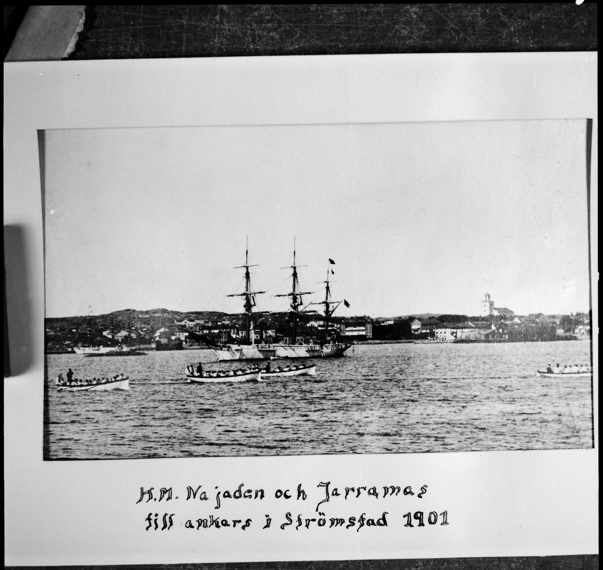 Bilden visar skeppsgossefartygen Najaden och Jarramas till ankars i Strömstad år 1901. I förgrunden syns fyra roddbåtar med skeppsgossar som förmodligen håller på med utbildning i rodd.