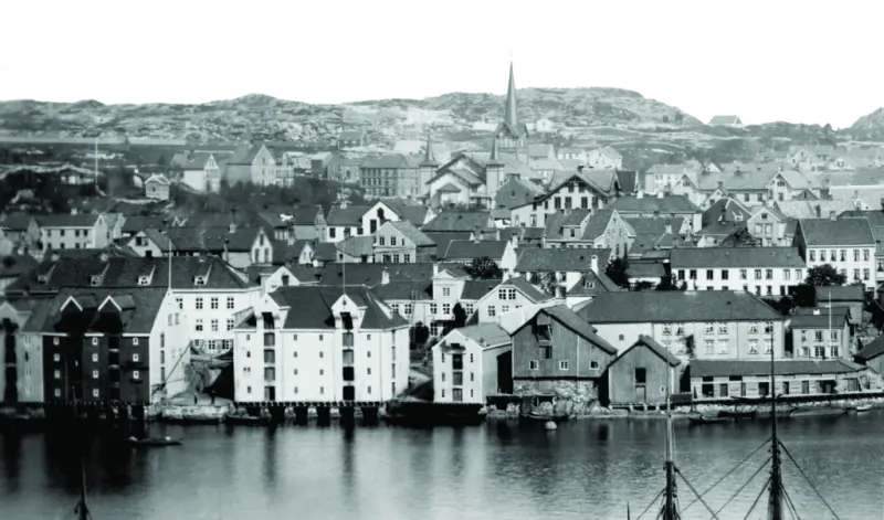 Clausengården til høyre, nærmest bryggene/ sjøkanten. kirka på Lyhshaugen i bakgrunnen. 1883.