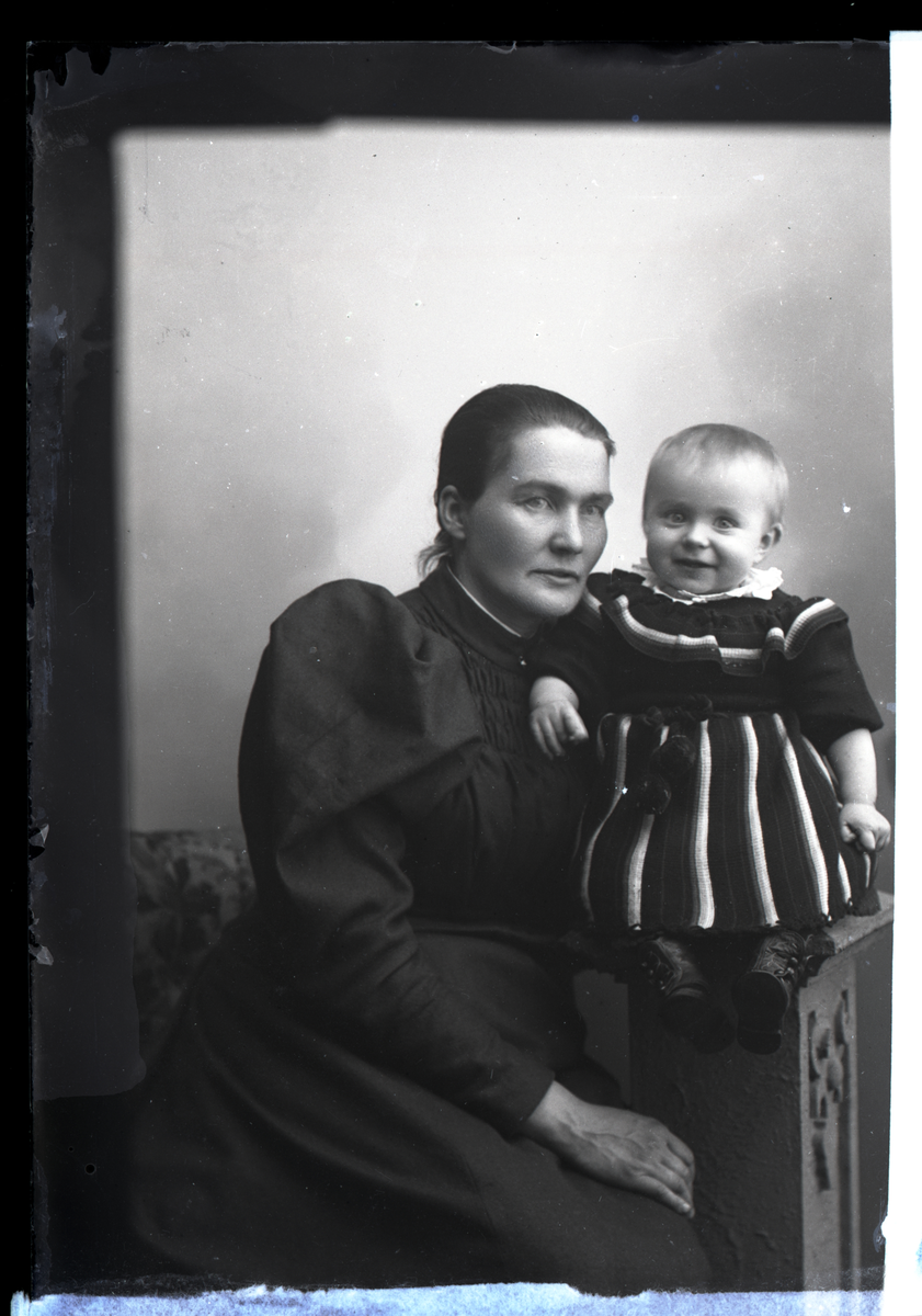 Atelierfoto. Portrett. En kvinne og et barn.
Skrevet på papir som er festet til negativet: 271   Oleane Foss, se bilde GM_MG.02470_1.
Oleane Johansdatter Foss f. Gullord (1865-1942). Søster til Marie Gullord. Barnet er identisk med barnet på 1183 «Maurids Foss». Oleane Foss finnes også på bildene GM_MG.01857, GM_MG.01858 og GM_MG.92280.