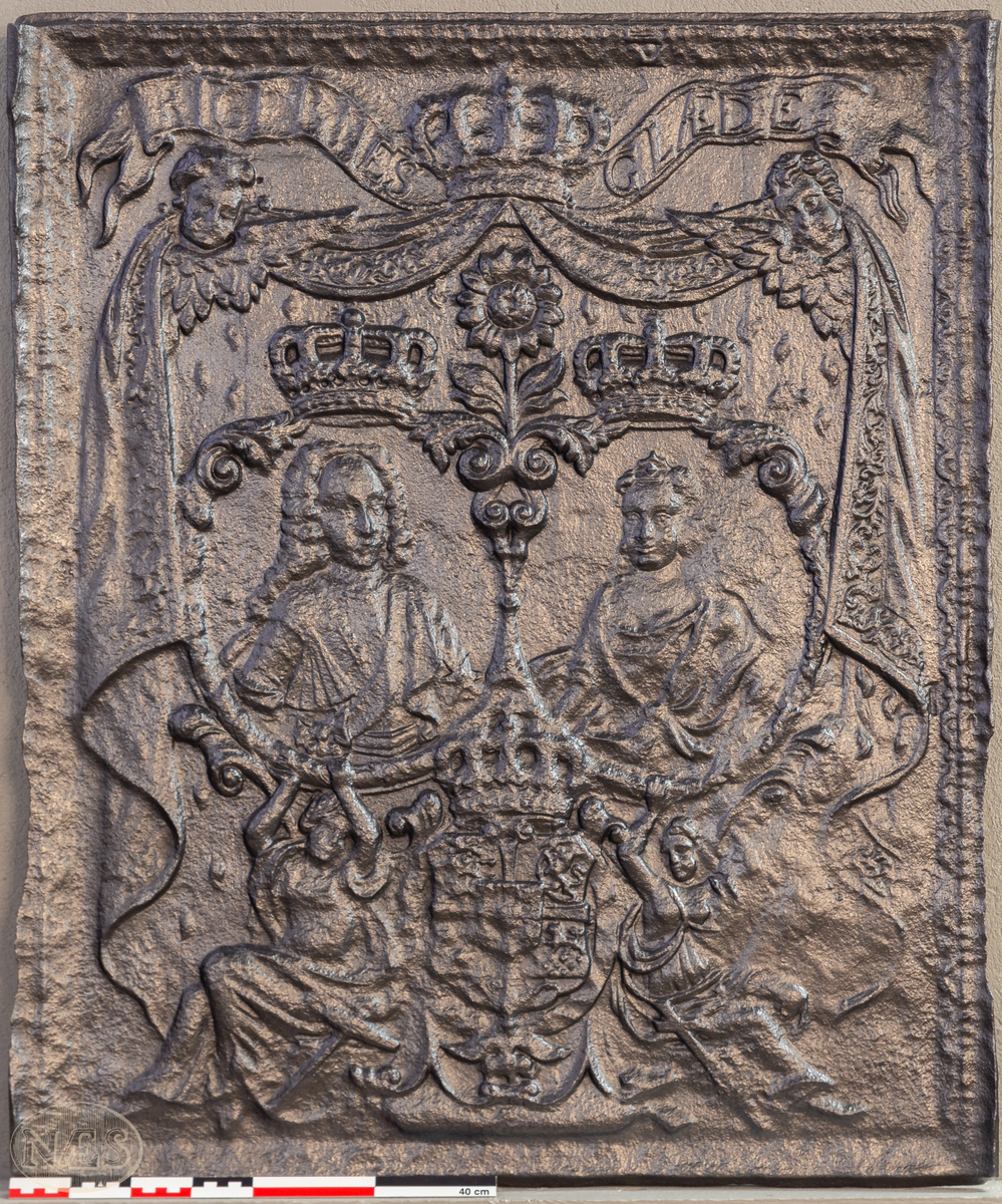 Stor langsideplate til kasseovn med brystbilde av Christian den 6 og Sofie Magdalena vendt mot midten. Motivene er plassert i hver sin medaljong. Omkranset av sittende allegoriske kvinnefigurer, de forenede rikers våpen og elefantorden. I bakgrunnen opphengte draperier. Øverst bøyet bånd med tekst. Ovnsplaten har faste skinner med bladornamentikk.