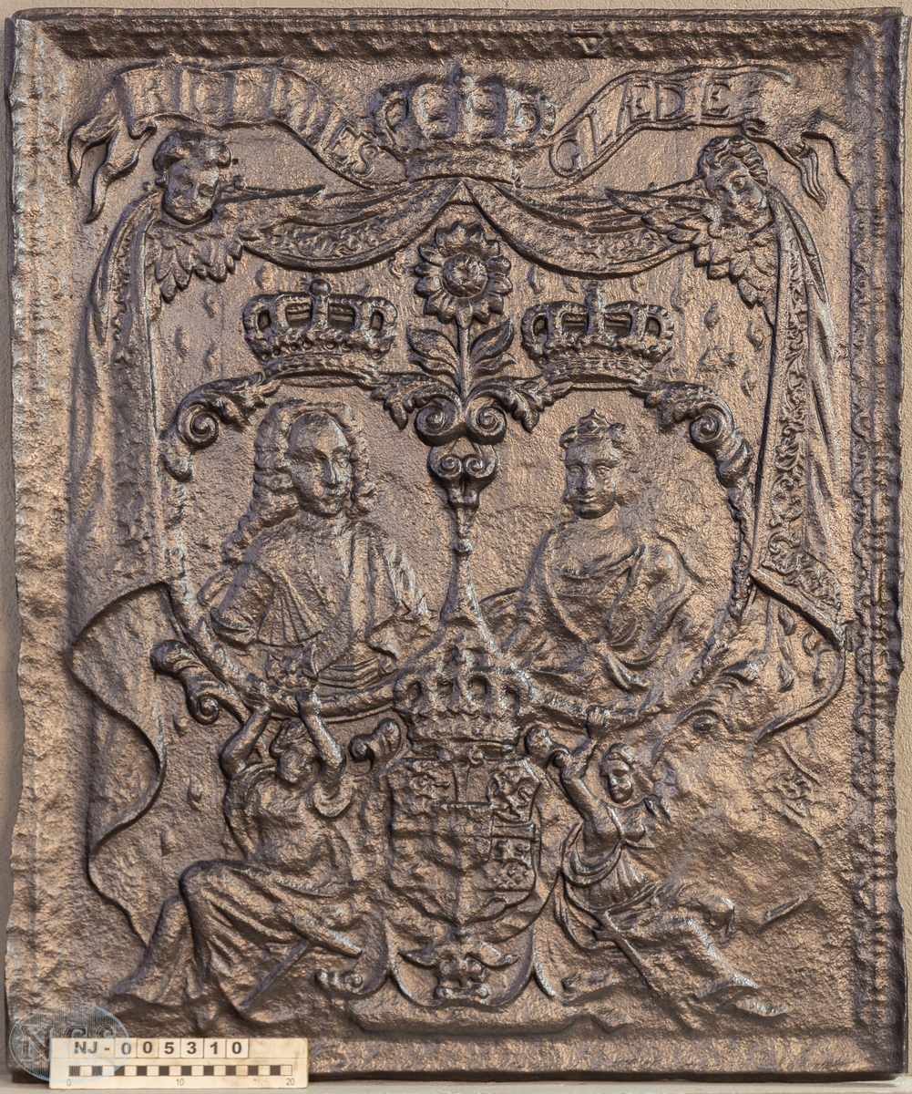 Stor langsideplate til kasseovn med brystbilde av Christian den 6 og Sofie Magdalena vendt mot midten. Motivene er plassert i hver sin medaljong. Omkranset av sittende allegoriske kvinnefigurer, de forenede rikers våpen og elefantorden. I bakgrunnen opphengte draperier. Øverst bøyet bånd med tekst. Ovnsplaten har faste skinner med bladornamentikk.