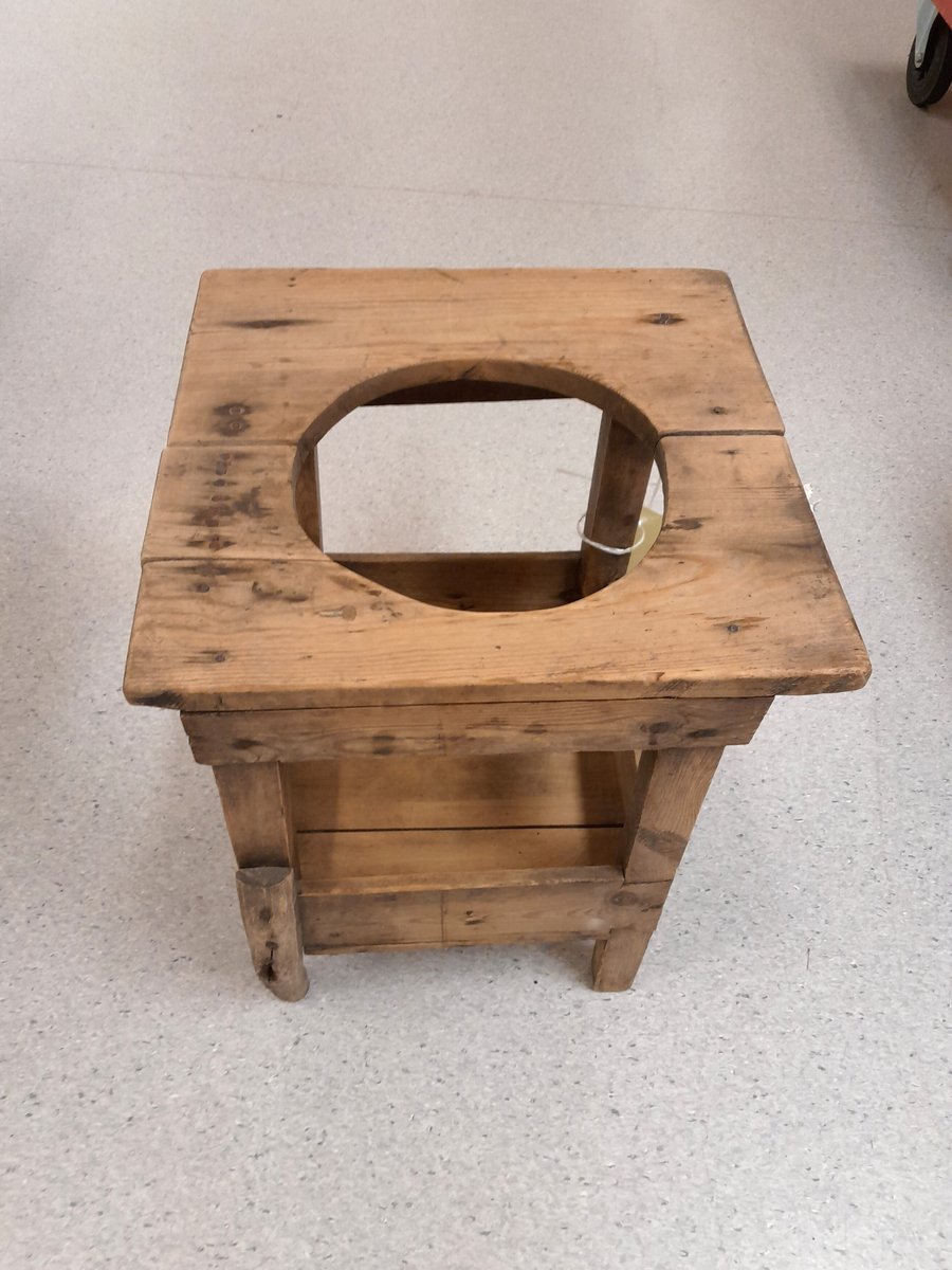 Ståstol (gåstol) for barn. Trekvit. Rundt hol i overplata. Fire rette firkanta bein. Underplate for føtene. 