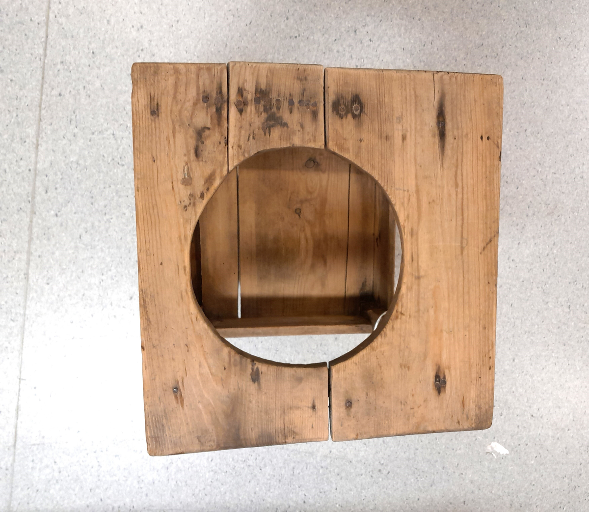 Ståstol (gåstol) for barn. Trekvit. Rundt hol i overplata. Fire rette firkanta bein. Underplate for føtene. 