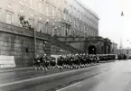 Högvakt, Stockholms slott,1972-03-19. 
Pågående vakt (med musikkår) ur I11 marscherar längs Lejonbacken, avgående vakt ur MP.
Mycket folk har samlats uppe på backen.