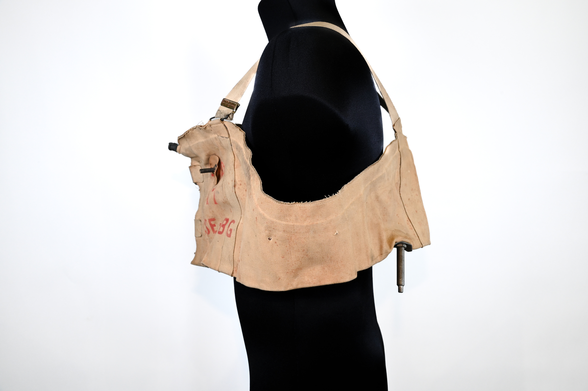 Flytväst, "The Auliff Lifebelt", uppblåsbar, tillverkad av duk och gummi, med metallfäste fram och axelband av tyg. Ursprunlingen var föremålet utrustad med en gasbehållare och ett metallhandtag som aktiverade uppblåsningsmekanismen. Flytvästen användes ovanpå flygardräkten och har därför en stor omkrets.