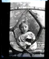 Atelierfoto. Et småbarn, en jente.
Skrevet på papir som er f