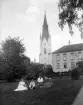 Tvivelsutan motiv från Linköping där stadens domkyrka och slott bildar fond. Mer oklart vad sällskapet beträffar, men efter fotografiets gåvogivare är medlemmar av familjen Sandberg ett rimligt antagande. I vilket fall som helst samlades sällskapet för fotografering i slottsparken. Tiden uppskattas till omkring 1910.