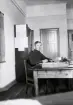 Repetitionsövningarna vid I11 i Växjö, hösten 1921.
6:e kompaniets expedition. En ung man i uniform sitter vid skrivbordet.