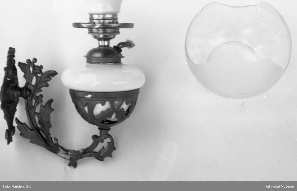 Vegghengt parafinlampe i rokokkostil med kolbe og skjerm.