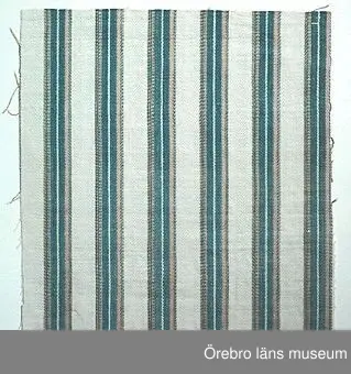 Prov av bolstervarstyg i oliksidig spetskypert med ränder i blått, vitt och ljust brun/beige i varpriktningen. Äldre föremål, enligt notering: "Gave til Örebro Hemslöjdsforening af Lea Åkerhielm Dylta Bruk d. 5.6.75". Ytterligare notering: "Bearbetning till Ö-o Läns Slöjdförenings 100-årsjubileum 1983, bolstervar IV" (se ÖLS121721 och ÖLS121722).Lea Åkerhielms födelsedatum är 1908-02-28. Se även Örebro läns Museums samling inv.nr ÖLM30.385:1-51.