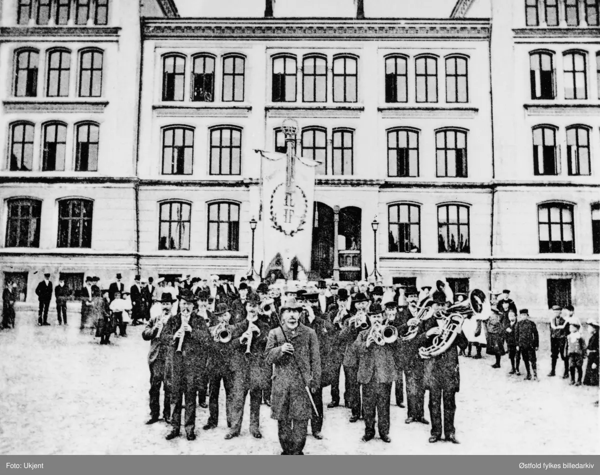 Fredrikshalds Turnforening feirer 25-årsjubileum i Halden 27. august 1904. Ukjent musikkorps oppstilt foran Halden offentlige høyere Almenskole (latinskolen).