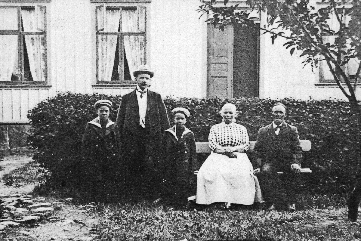 "Lelle-Johan" med familj på Slottsgatan 13, Lotsen 3 i Varberg. Johan Andersson sitter längst till höger med hustrun Dorothea, "Thea". Deras son Fredrik Andersson, typograf på Norsteds i Stockholm, är på besök omkring 1913 med sina två söner Åke (f. 1908-03-09) till höger och Erik (f. 1905-11-06) till vänster. Hustrun Gerda tar bilden. 

När Johan och Thea gifte sig 1878 noterades han som bärare, fd sjöman, och husägare i kvarter IV, men 1884 stod Johan som ägare till fastigheten på Platsarna. Han var fiskare men om somrarna körde han även badgäster till Getterön. Thea var från Polen och arbetade som baderska i badhuset. Johan försvann till sjöss utan att bli återfunnen, men Thea levde till 1923. Fastigheten kallades sedan "Thea-Eriks" och "Tamms", efter ägaren P G Tamm 1919-1924.