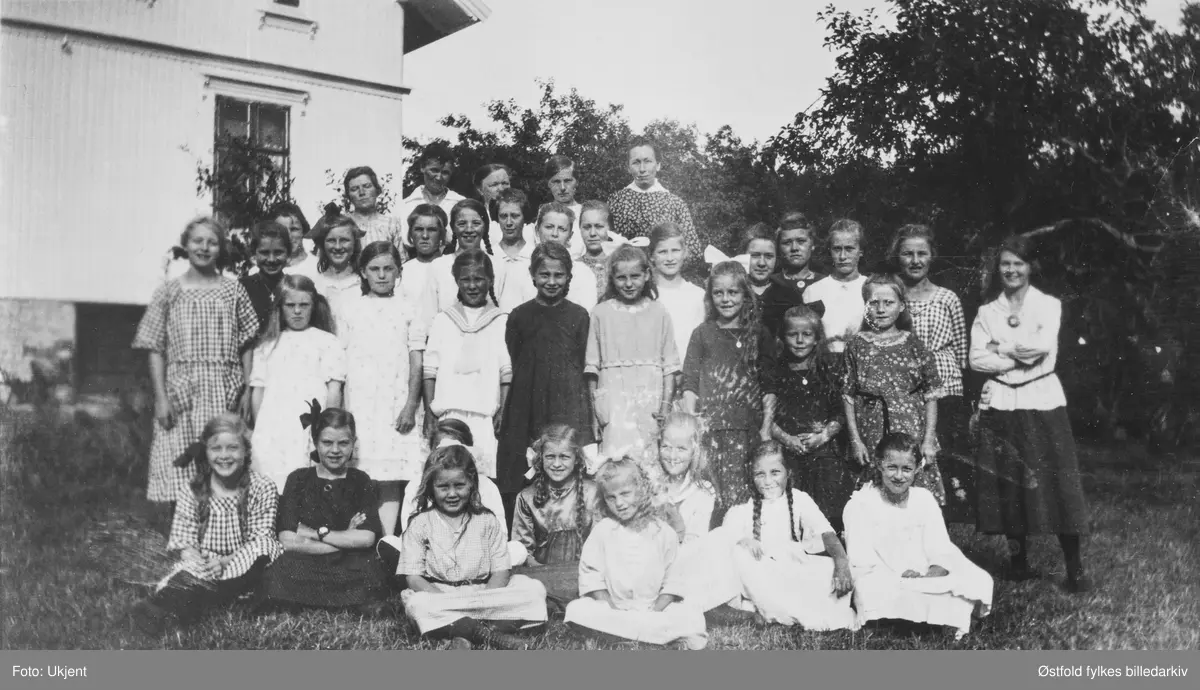 Barneforeningen "Blåveisen" Østaskog i Varteig ca. 1923. Startet ca 1915 av Norsk Misjons Selskap (NMS). I 1928 ble foreinga tilknytta Finnemisjonen (same). Forening ble stifta av bl.a.  Gunda Kingsrød og Inga Lindemark. Bildet er tatt på gården  Lindemark. Navneliste med plassering se fotokort.