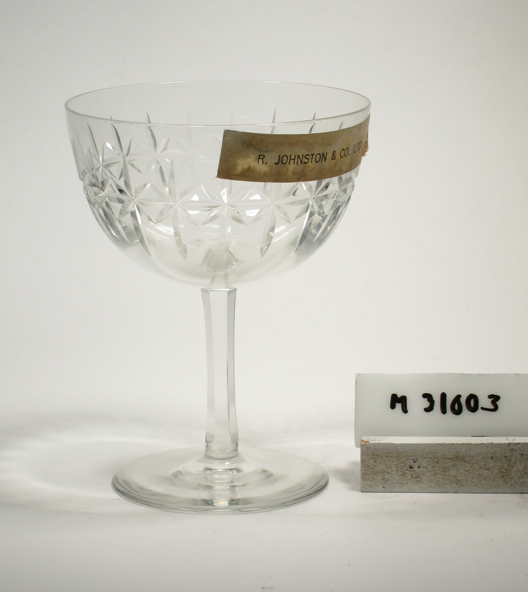 Formgivare: Edvin Ollers. Champagneglas på ben och fot. Tulpanformad, vid kupa med skärslipning. Fasettslipat ben.